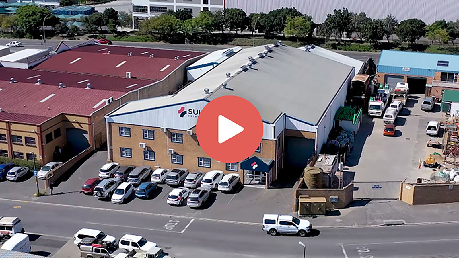 Aerial view of Sullwald Printing Solutions building with parked cars and delivery trucks outside.