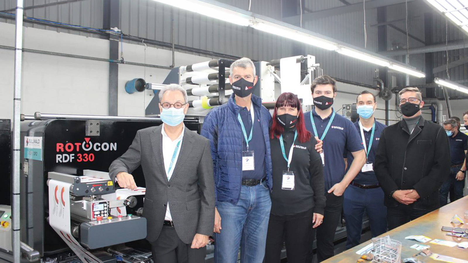 Rotocon CEO Michael Aengenvoort standing with Sullwald Printing owner Marius Sullwald with this with wife, son Heinrich and other individuals in front of a ROTOCON RDF 330 in factory.