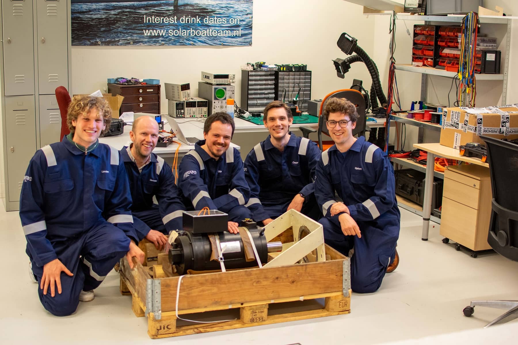 Photo of Flying Fish engineers in their workshop, posing with an electric maritime motor.