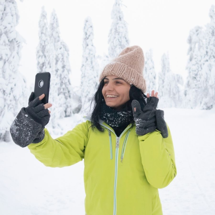 Woman making video on phone in snow.