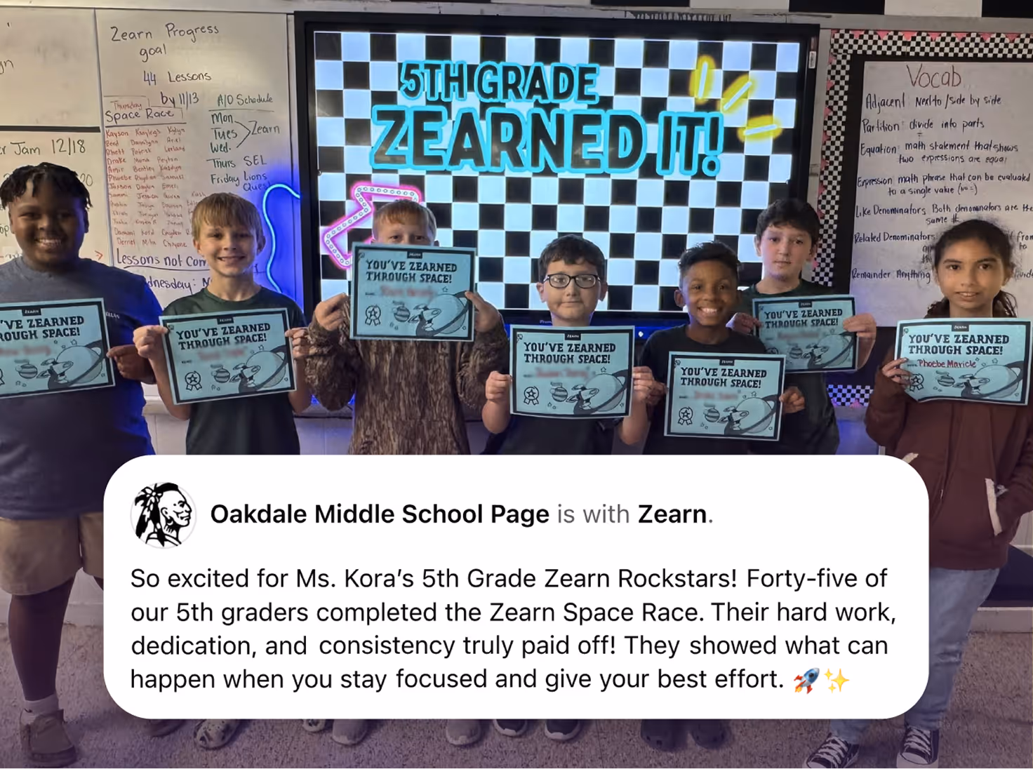 Seven 5th graders holding 'You've Zearned Through Space!' certificates in front of a 5th grade Zearn sign.