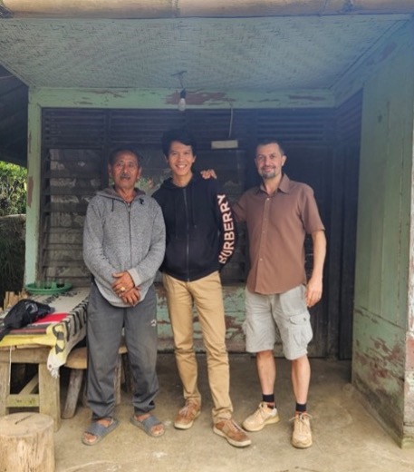 A farmer stands with project managers on site at a coffee plantation
