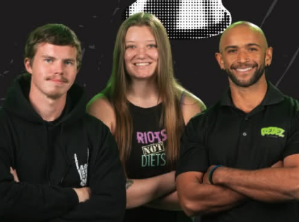 A fitness team posing for a picture inside of a gym