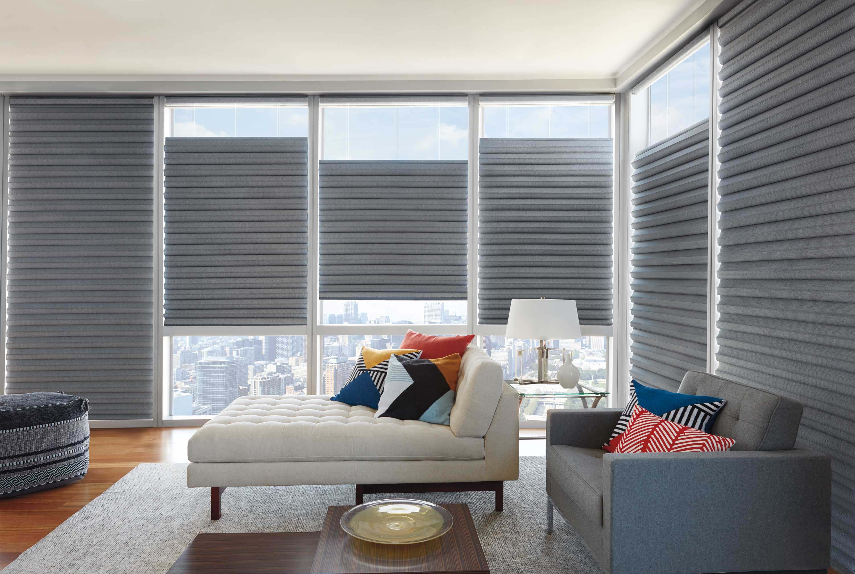 Room with gray motorized window shades, modern furniture, and city view.