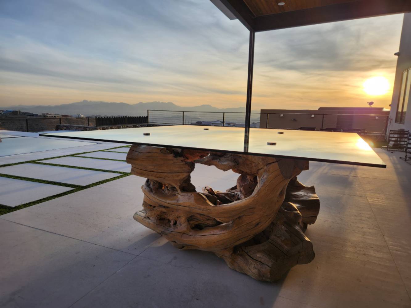Modern outdoor table with driftwood base at sunset.