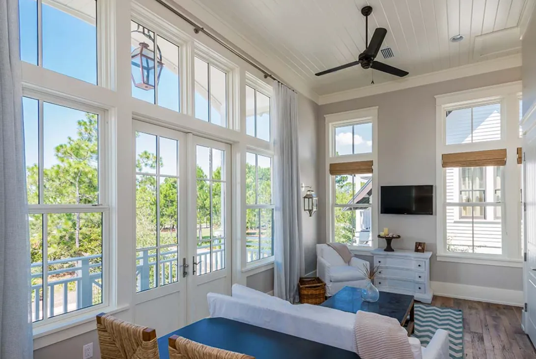 Bright living room with large windows, ceiling fan, and patio view.