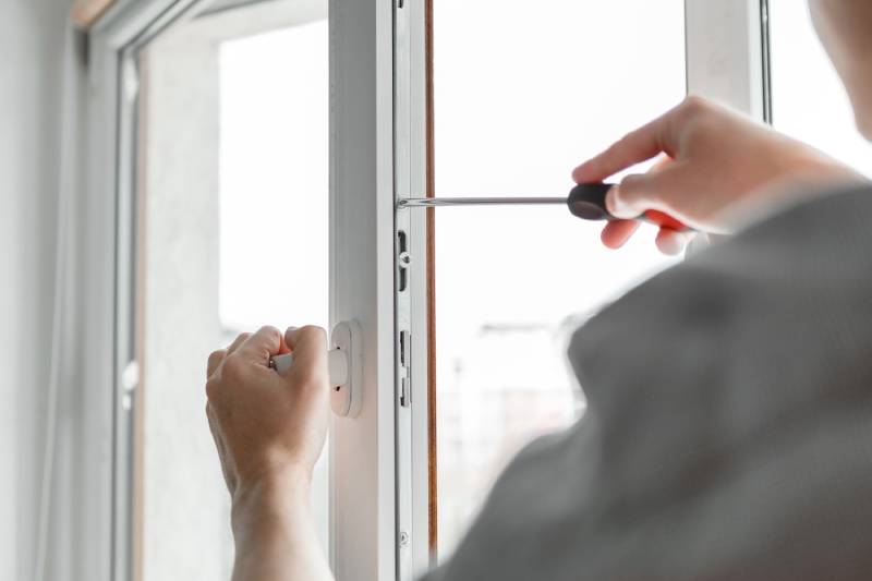 Person using screwdriver on window frame