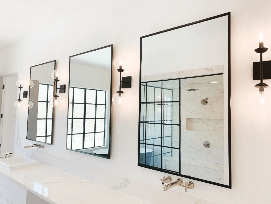 Modern bathroom with large mirrors and black framed shower partition in Las Vegas.