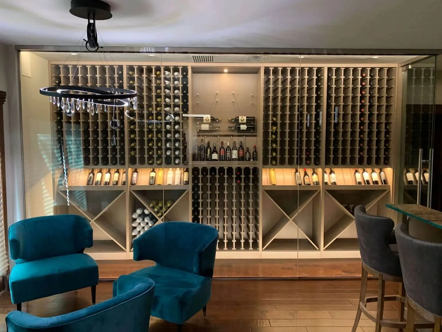 Modern glass wine cellar with teal chairs in front