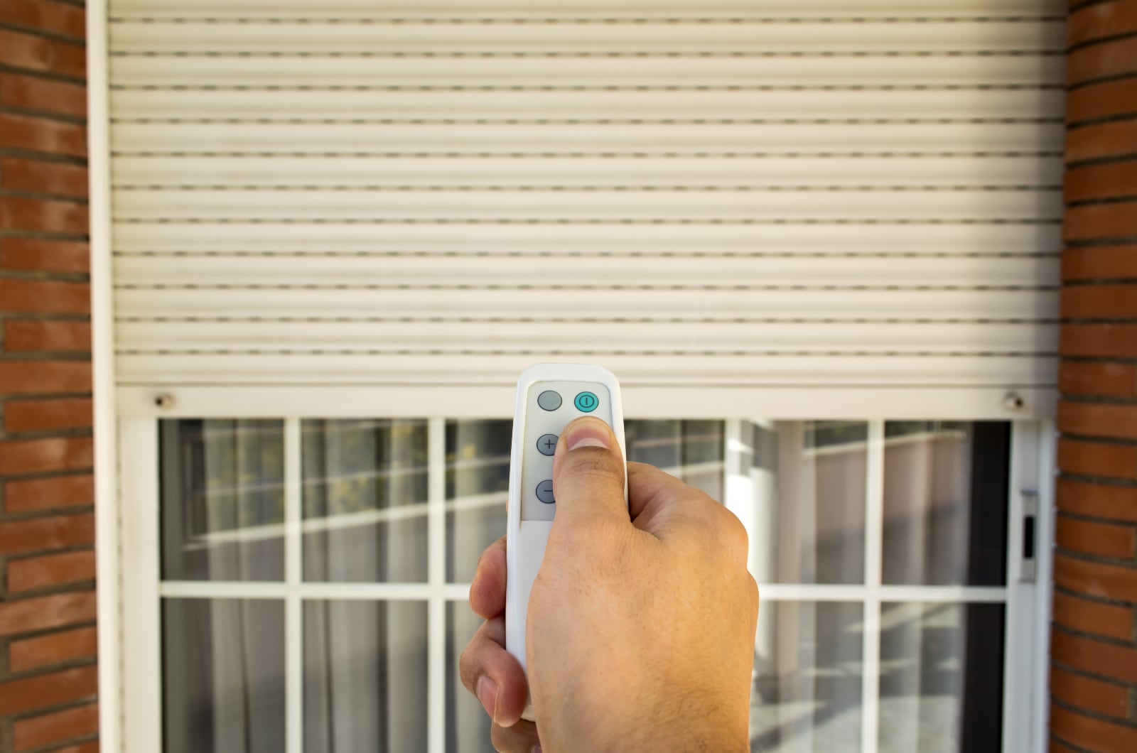 Hand holding remote for motorized shutter.