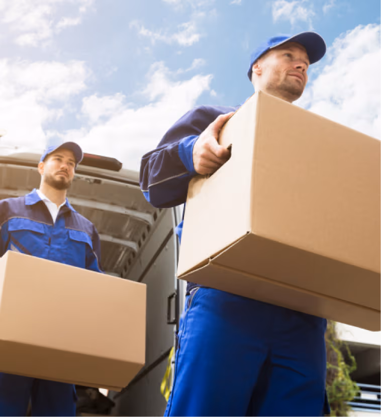 Two delivery workers carrying cardboard boxes from a truck in bright daylight