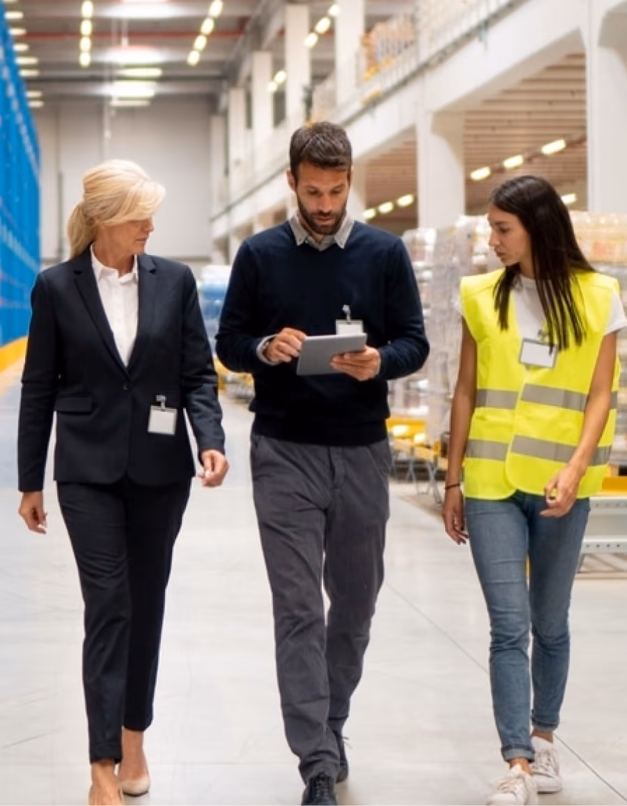 team of three professionals walking through a warehouse, discussing logistics and operations