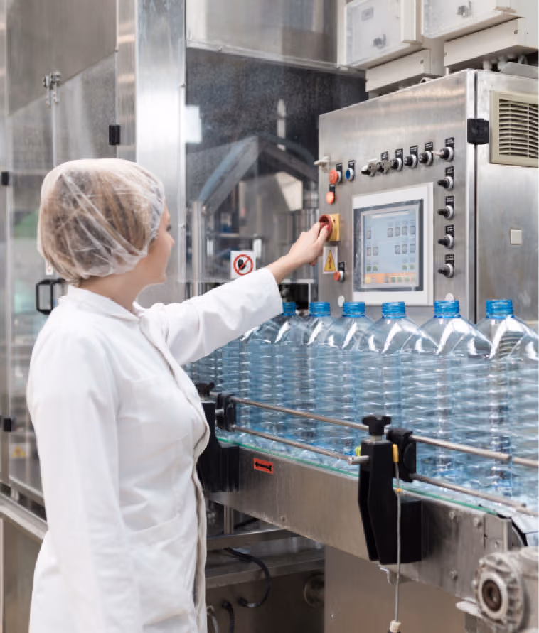 technician operating a water bottling machine in a production facility