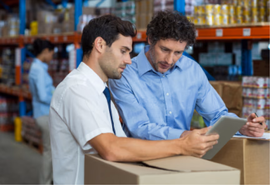 Two professionals discussing on a tablet in a warehouse setting