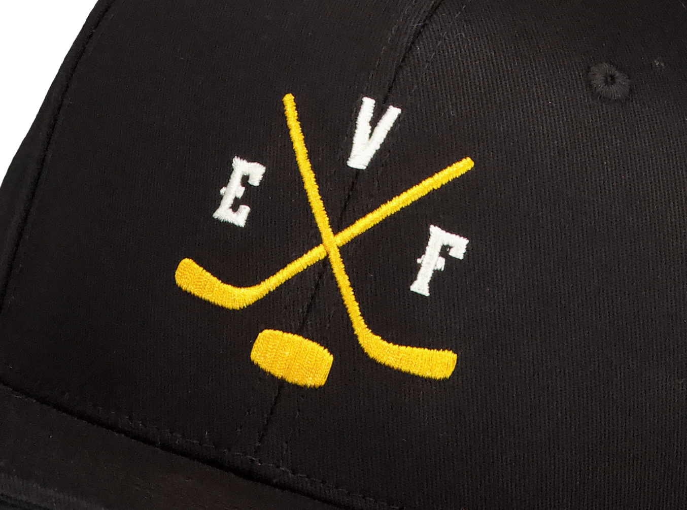 Black cap with yellow embroidered crossed hockey sticks and puck, and white letters E, V, F around the sticks.