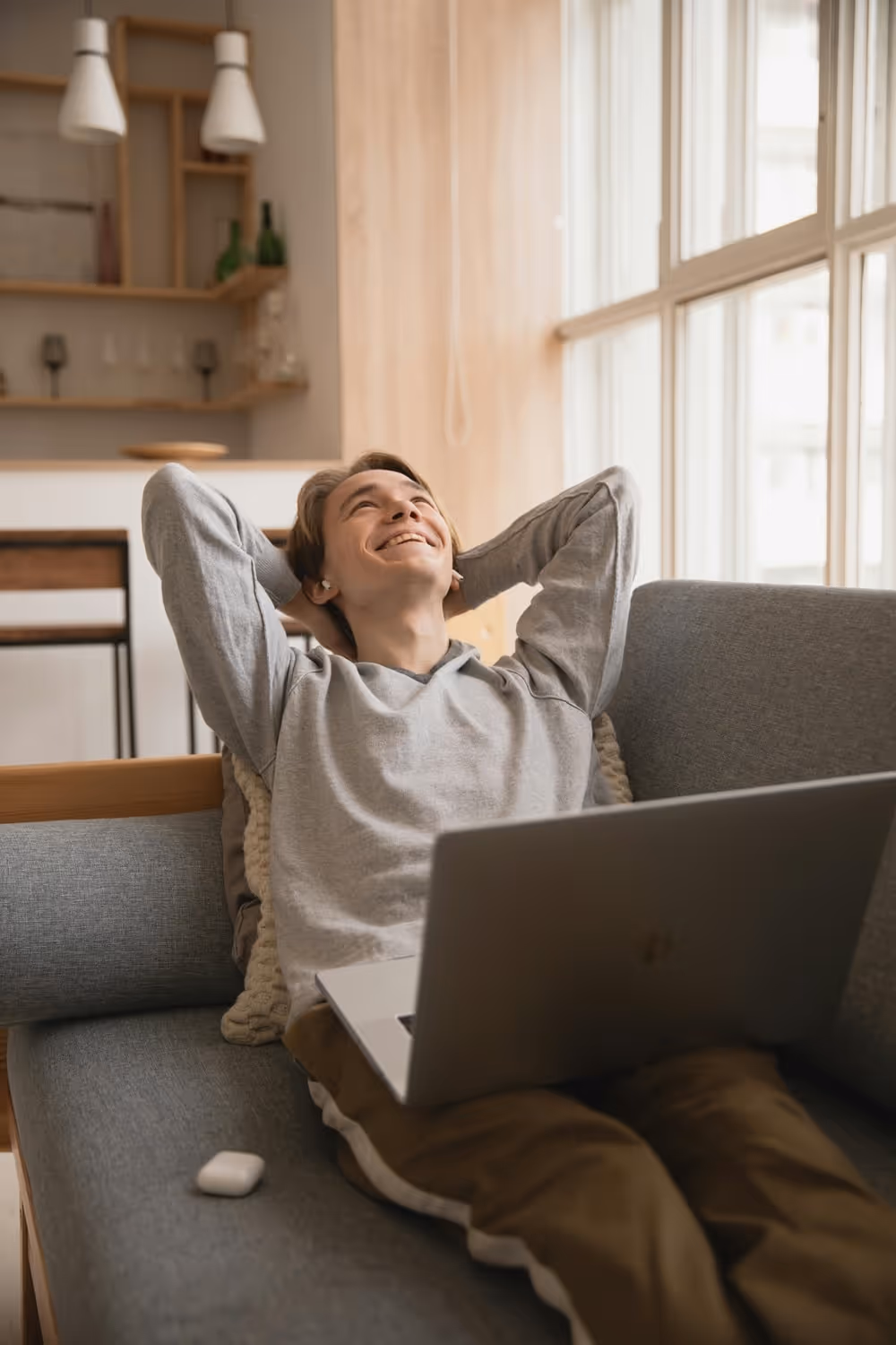 Man sitting with a laptop on his lap, looking happy and laughing