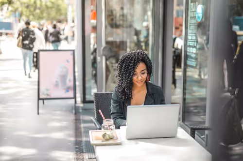 A parents or guardian using Boilerplate enrollment portals sitting outside a coffee shop
