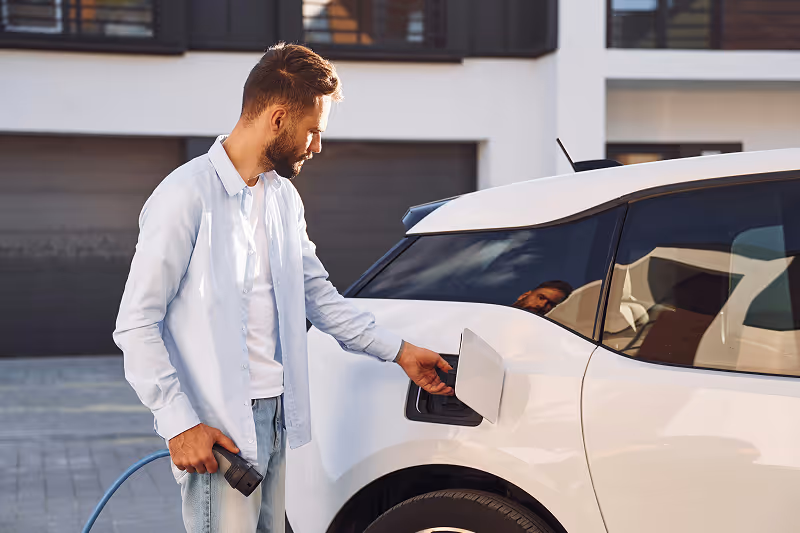 A man washing a white car with a hose.