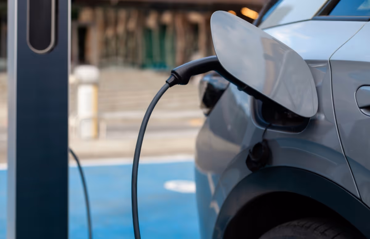Close-up of a silver electric car charging at a public charging station.
