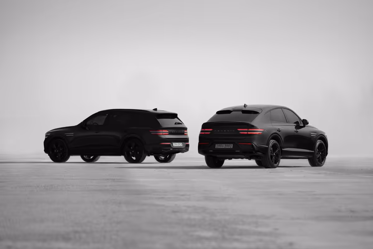 Two black luxury SUVs parked side by side on a flat, gray surface with a minimal gray background.