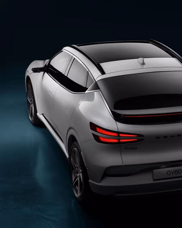 Rear-side view of a sleek white electric SUV with LED taillights and tinted windows on a dark background.