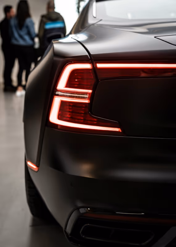 The tail lights of a black car in a showroom.