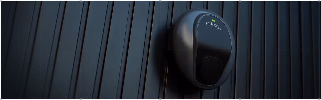 Black Pod Point electric vehicle charging station mounted on a dark vertical panel wall with a green indicator light on.
