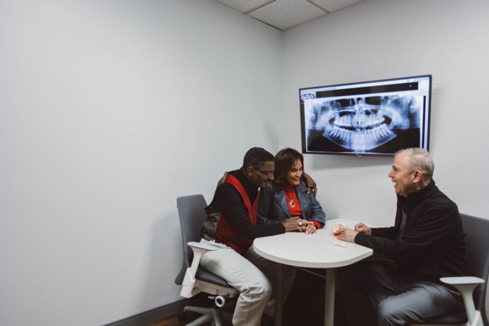 Two dental professionals reviewing a CEREC crown design on a monitor in a consultation room.