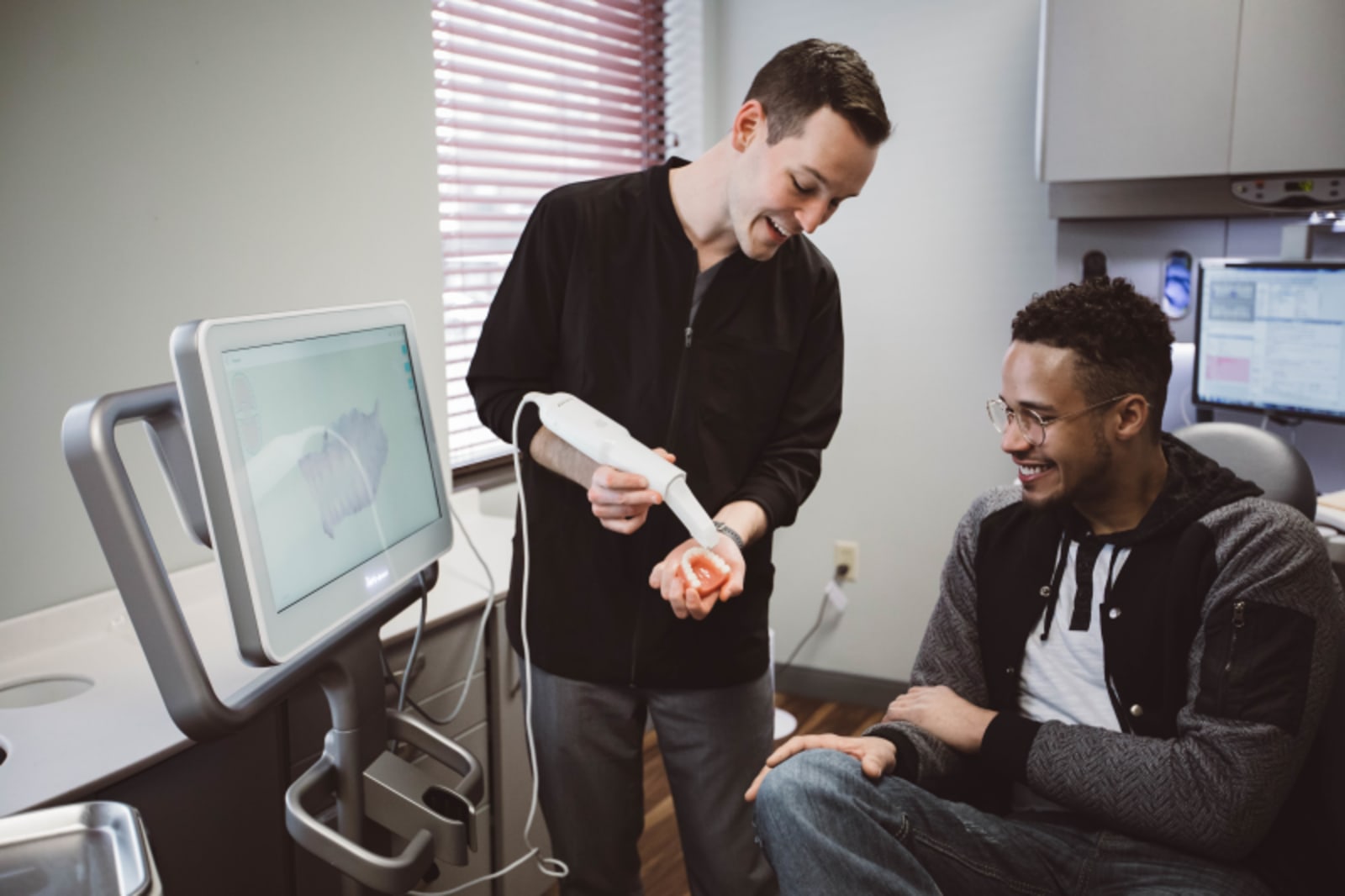 Dentist reviewing digital scan on monitor with patient in treatment chair