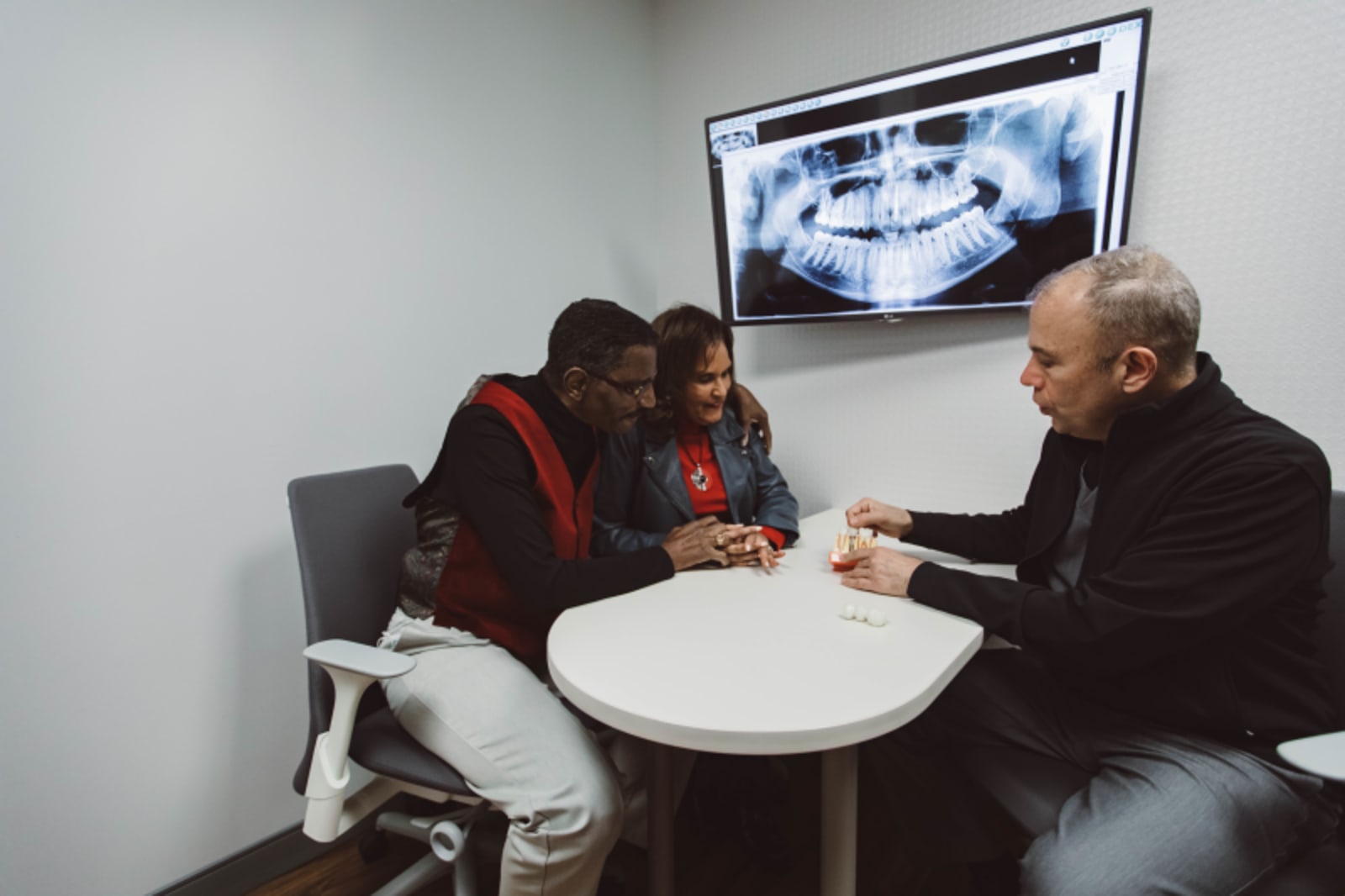 Three people reviewing dental imaging on screen during treatment discussion