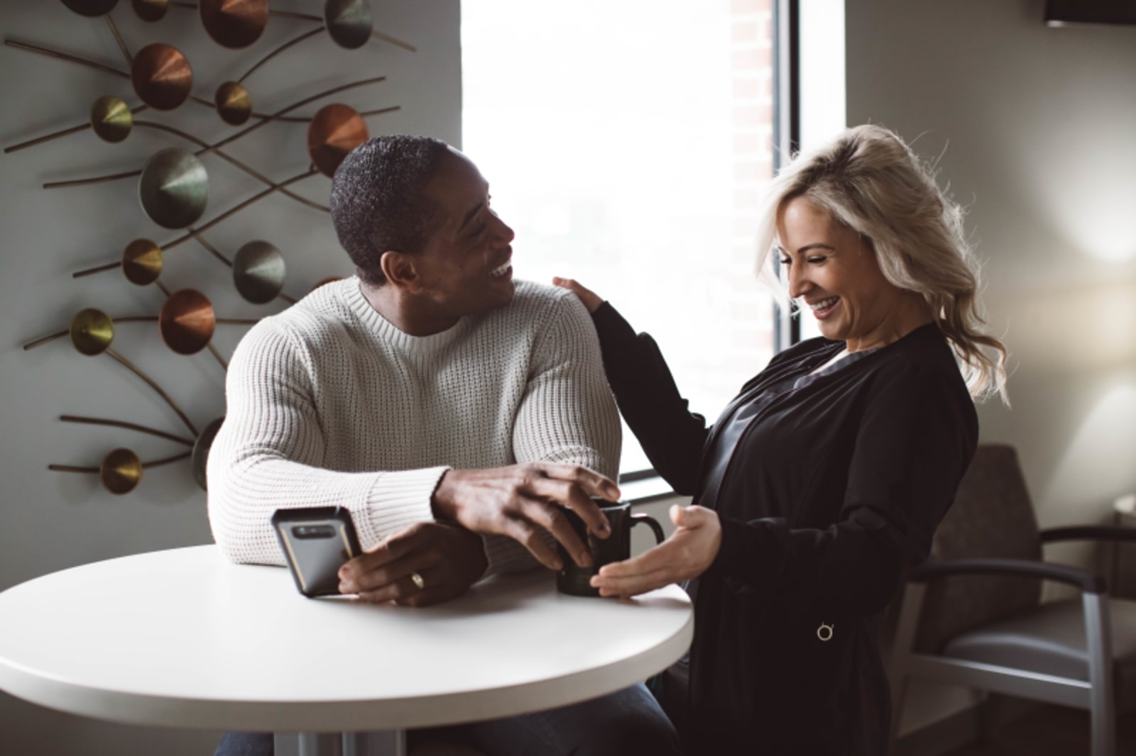 Dentist and patient discussing concerns at a consultation table in a modern dental office.