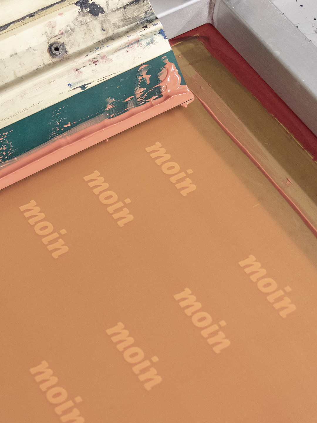 Siebdruck Sieb mit orangener Farbe und Rakel