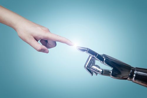 Artificial machine hand pointing out to touch a human hand and finger