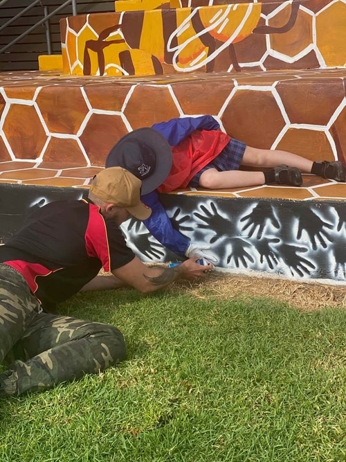 Hunter Barnes painting a moral with a student