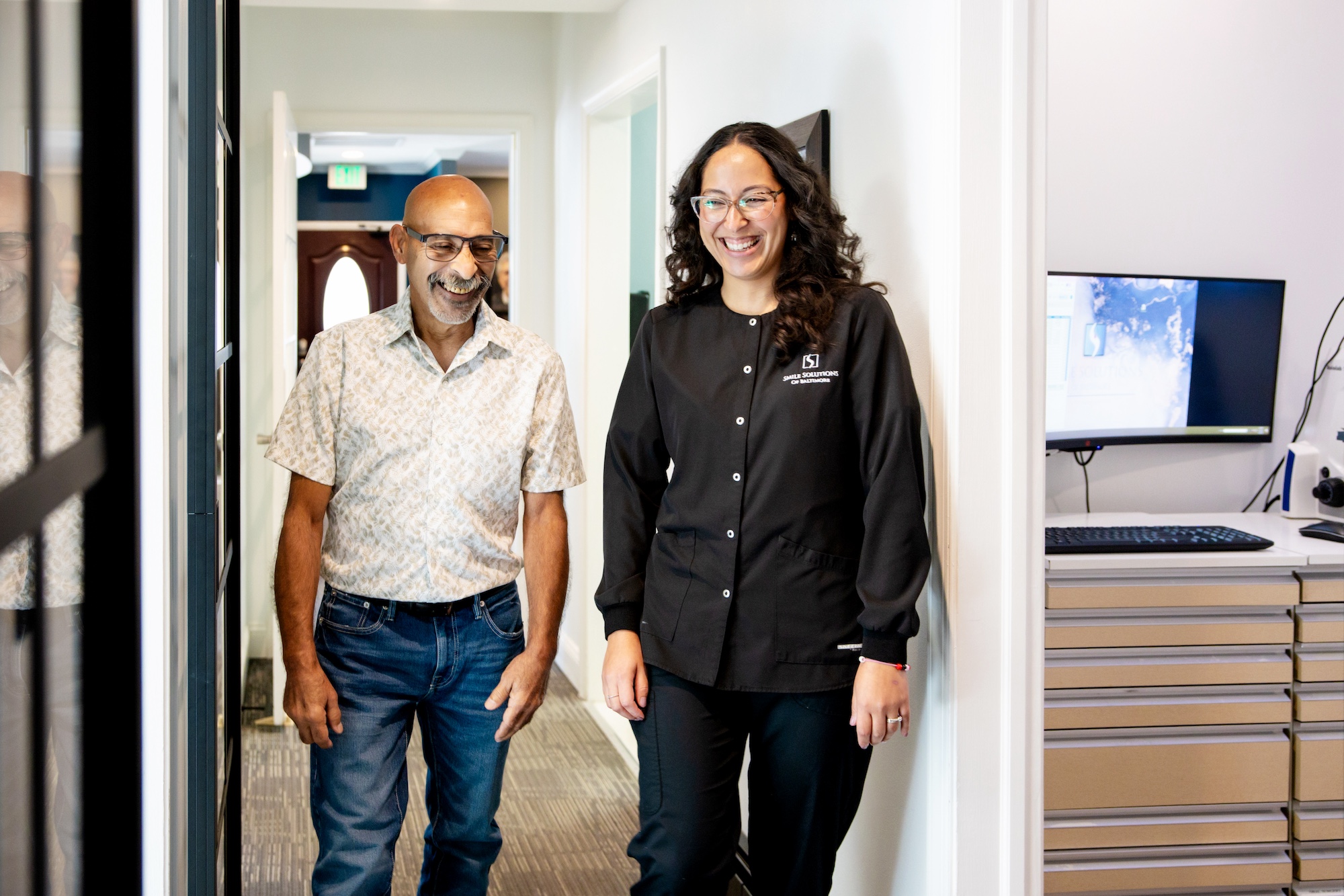 A dental assistant escorts a male patient down the hallway at Smile Solutions of Baltimore.