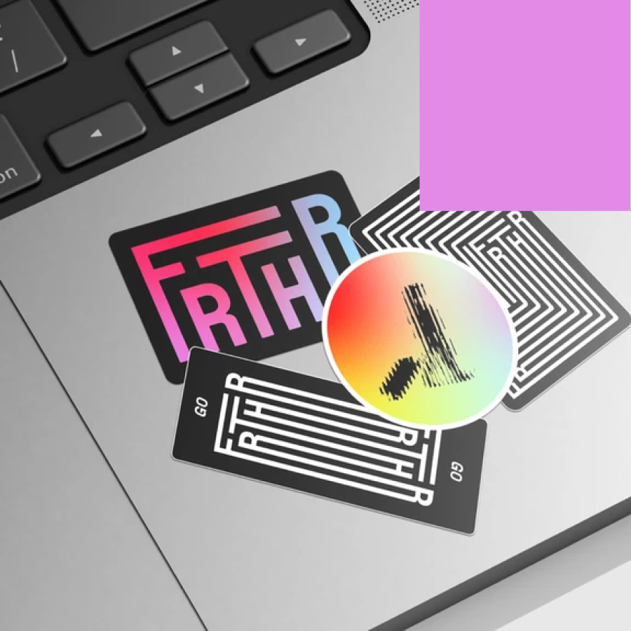 FRTHR branded stickers arranged on a laptop — the gradient logotype, black and white maze-pattern versions marked “GO”, and a circular rainbow gradient sticker.