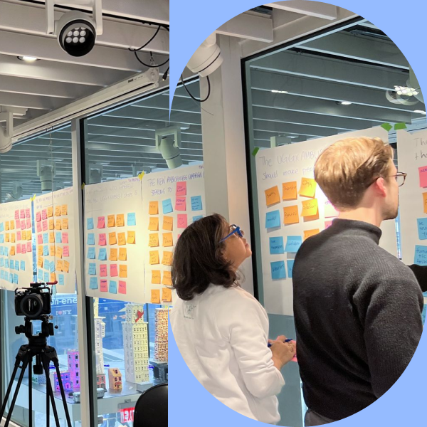 Two workshop participants adding sticky notes to whiteboards covered in UGG × AMBUSH campaign prompts, with a video camera on a tripod recording the session.