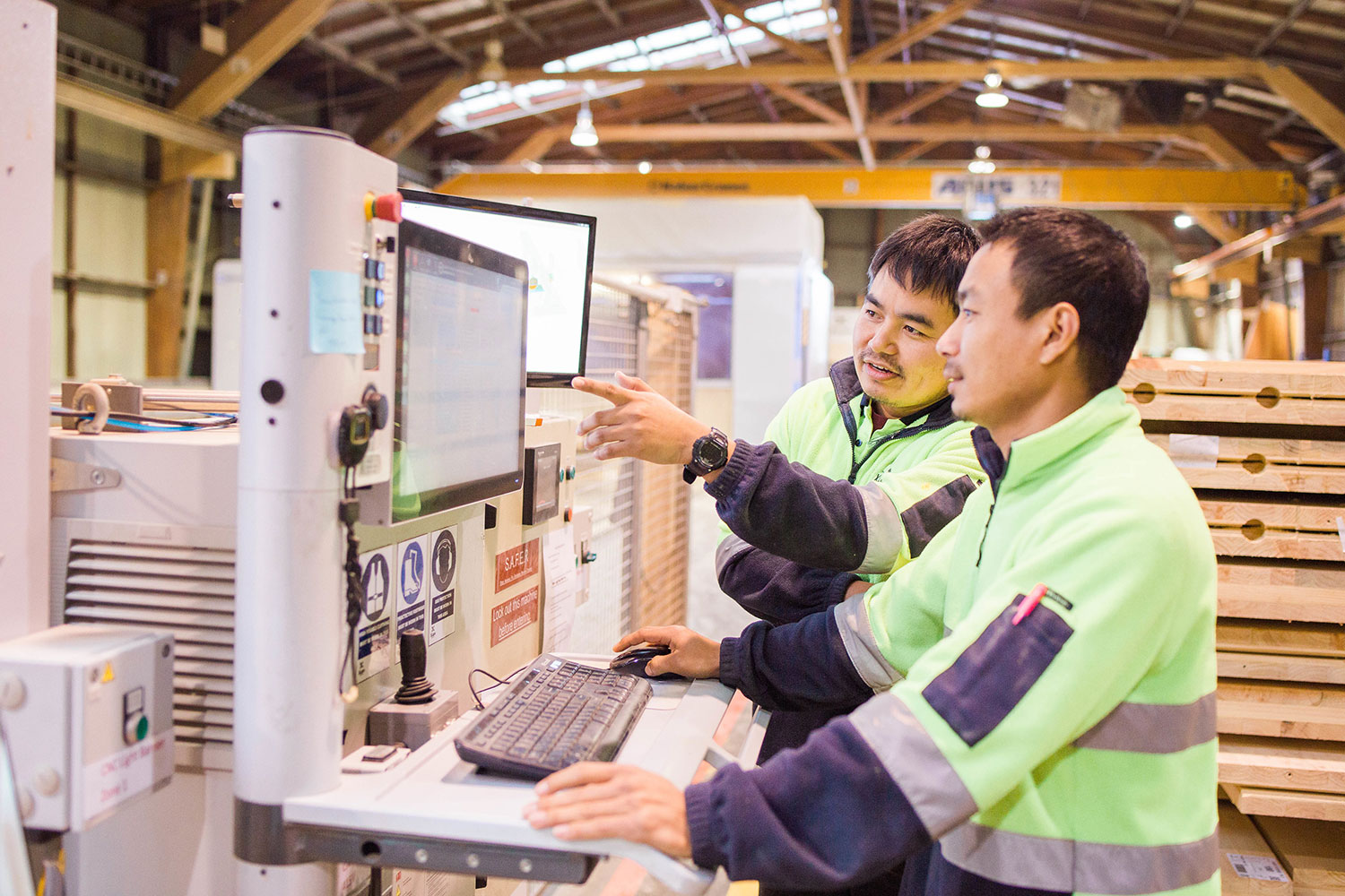 Two workers in hi-vis clothing look at computer screen