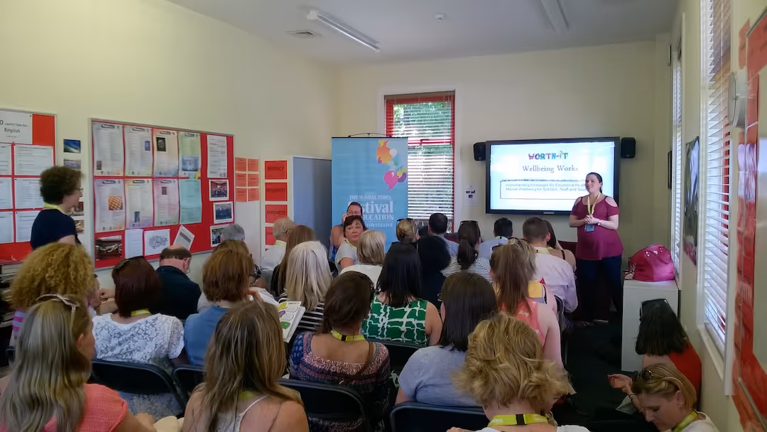 Liz giving presentation on wellbeing to audience seated in a classroom setting.