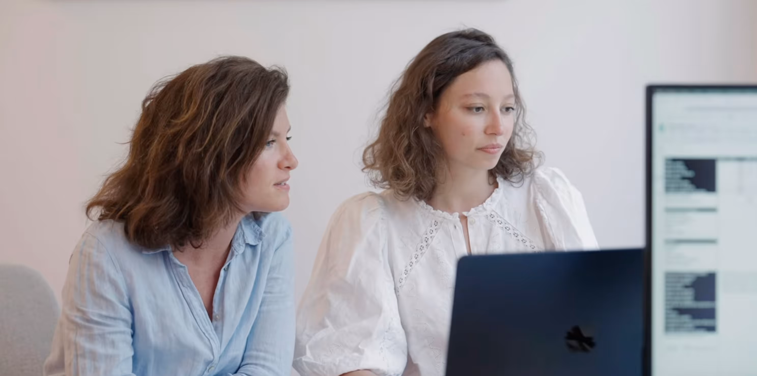 Deux membres de l'équipe Timescope concentrées regardant un écran d'ordinateur dans un environnement de bureau moderne.