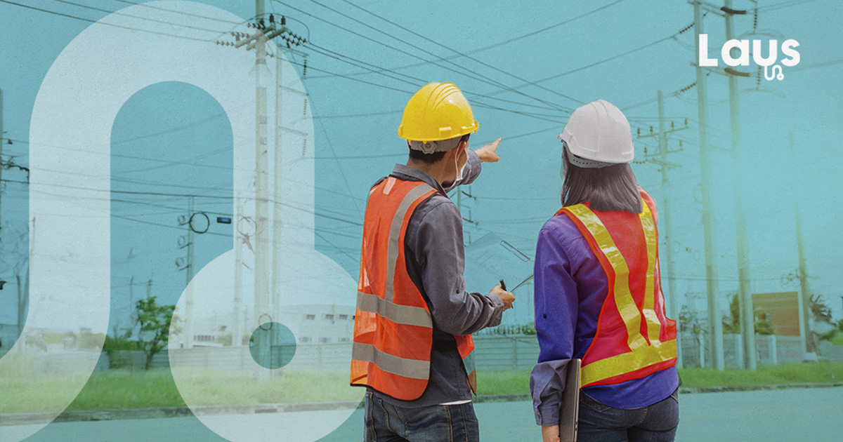 Trabajadores con casco y chaleco de seguridad inspeccionan una zona de tendido eléctrico en obra, representando la prevención de riesgos.