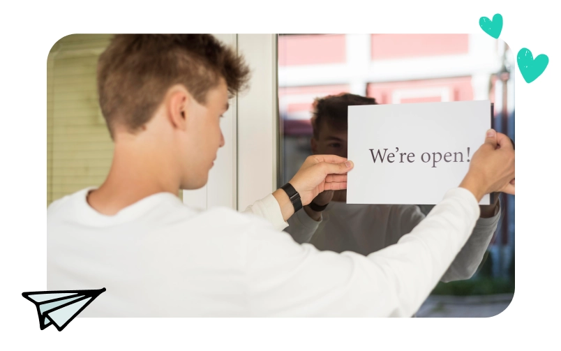 An individual hangs up an exterior open sign on their business window