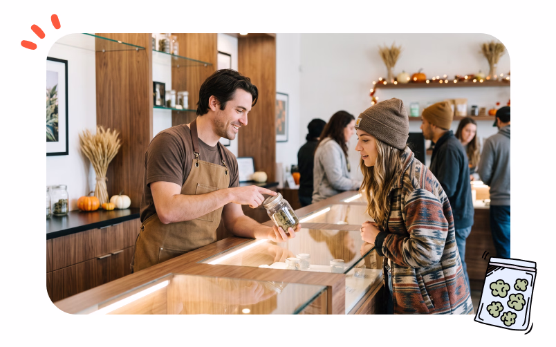 A smiling budtender is recommending a product to an intrigued customer.