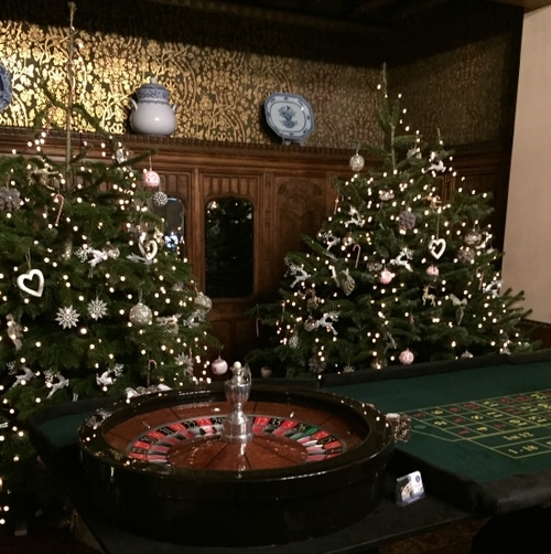 A couple fully decorated Christmas trees behind a roulette table