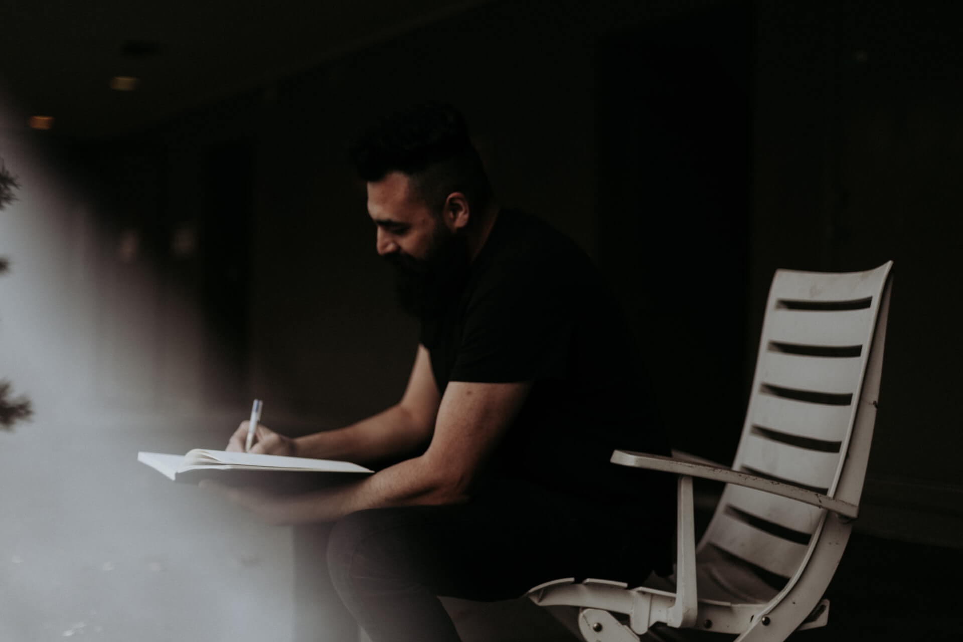 Guy sitting on a chair writing in his journal