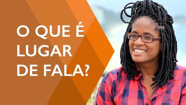 Imagem de uma mulher, jovem e negra, usando uma camisa xadrez, óculos e várias trancinhas no cabelo, ela está sorrindo. Ao seu lado está escrito: "O que é lugar de fala?"