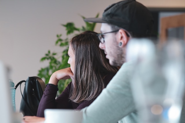 A couple sitting side on to the camera looking away from the camera in a cafe.