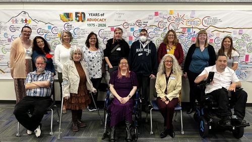 DDC Council members smile in front of poster celebrating 50 years of WADDC