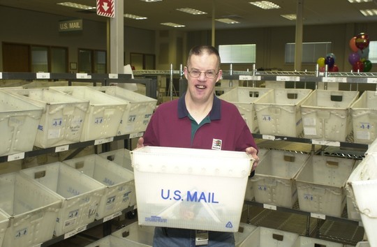 Dan Thompson in the Microsoft mailroom holding a mail receptacle