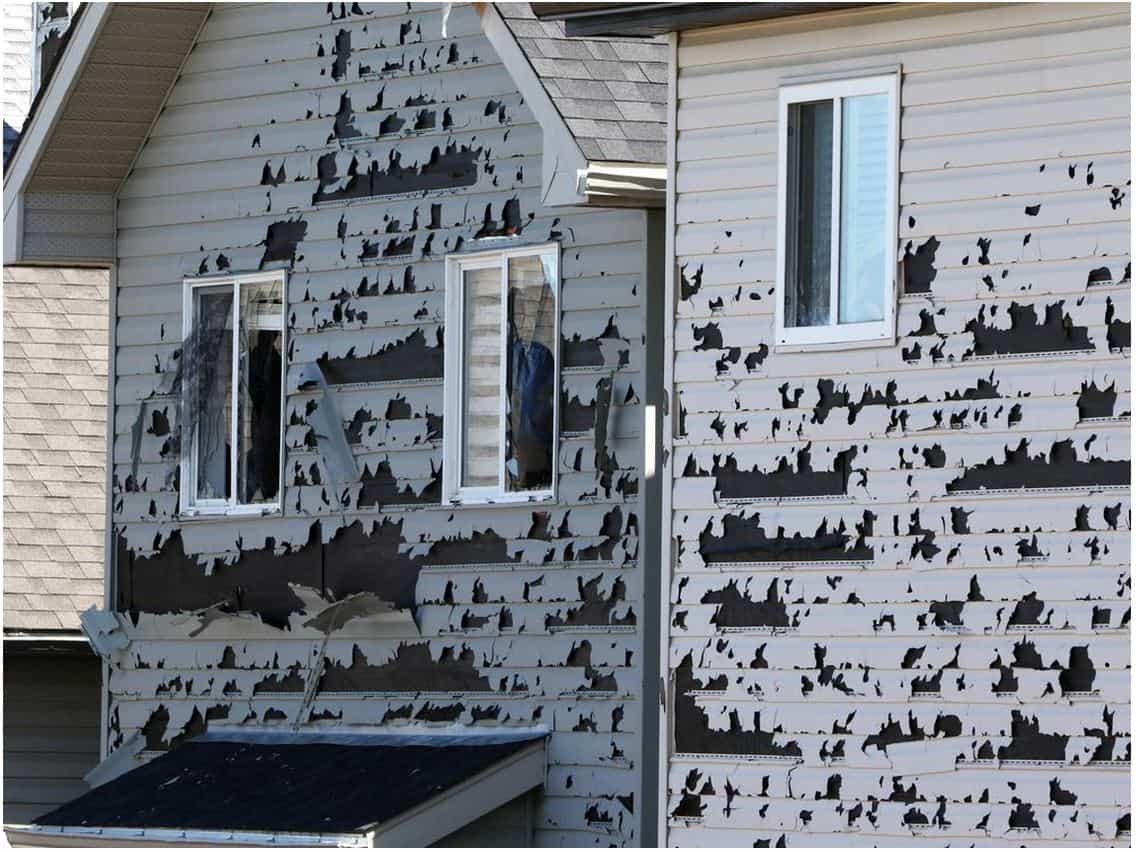 House with black weather-resistant paper on the siding, with windows partially installed, construction phase.